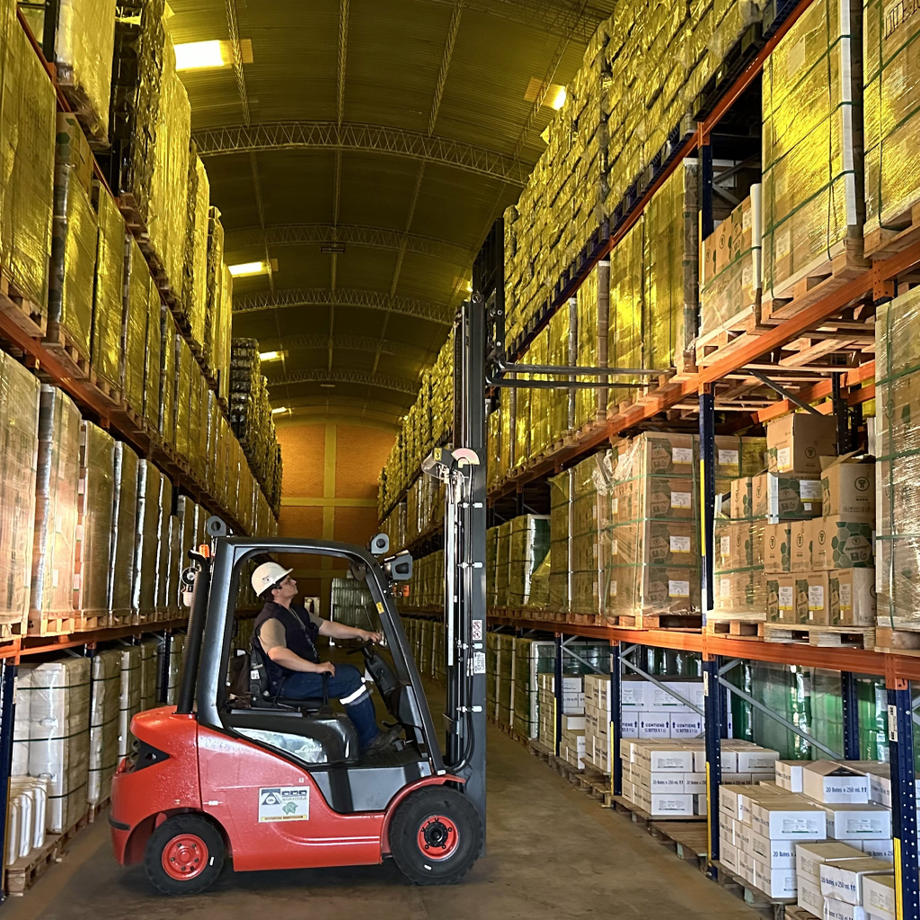 Trabajador usando montacargas para bajar mercaderia del rack